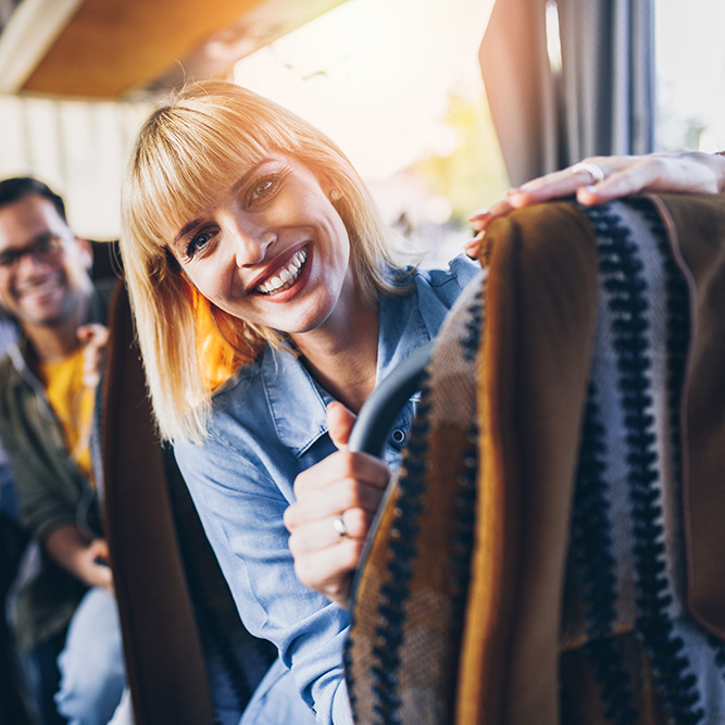 Frau sitzt glücklich im Bus während ihrer Reise mit FGS-Reisen